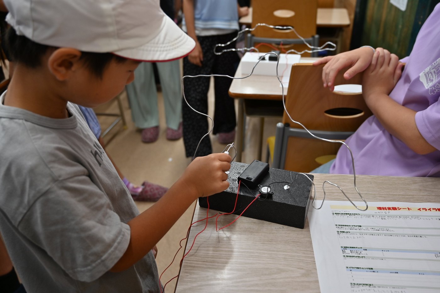 導線とワイヤーをつないでイライラ棒を組み立てる小学生