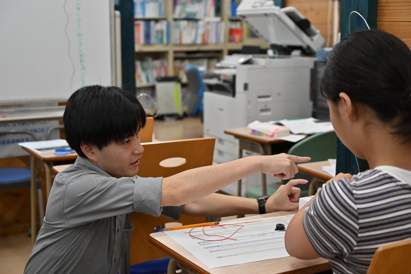 実験シートを指さして生徒に説明する先生