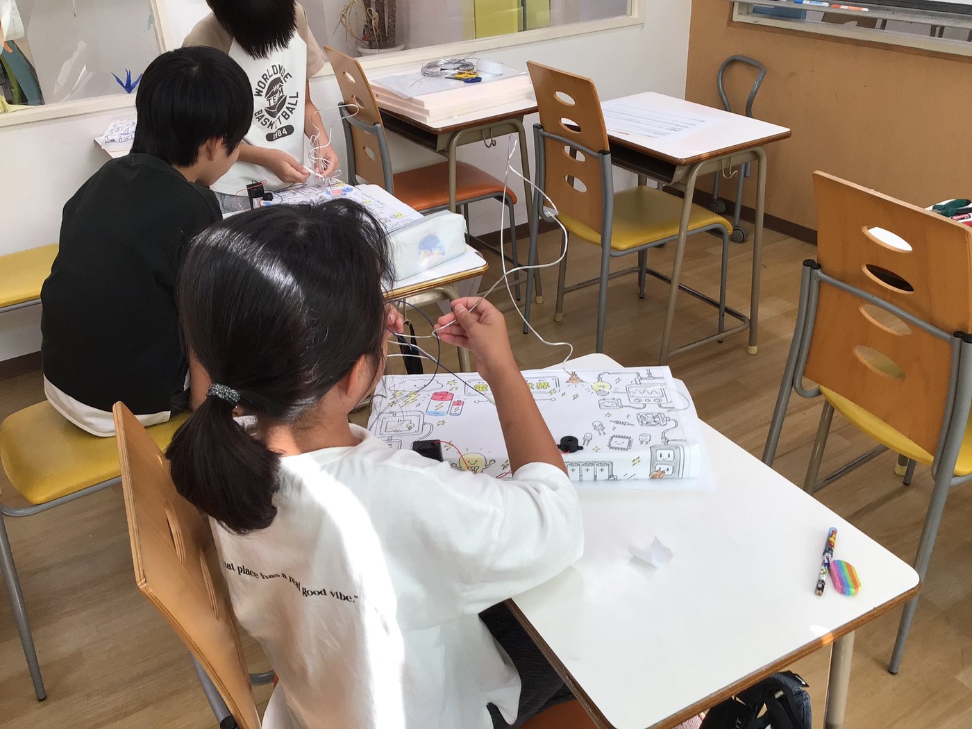 大久保教室でそれぞれ自分の台紙に向かって作業する小学生たち